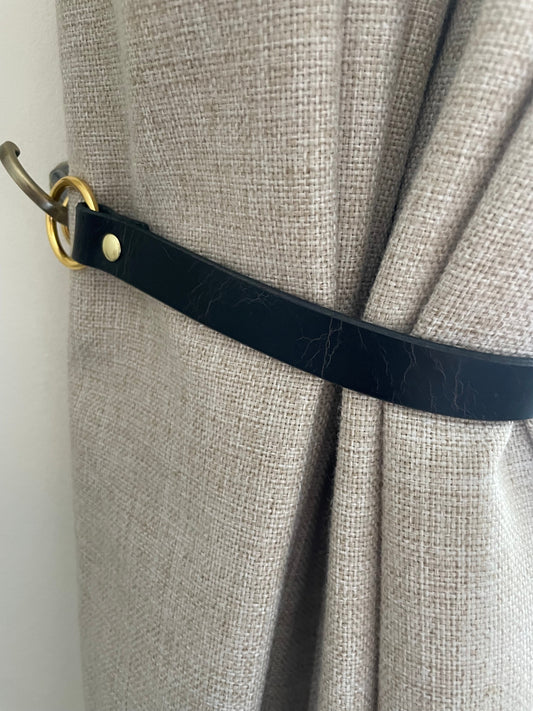 Handmade leather curtain tie backs styled on linen curtains in a bright living room