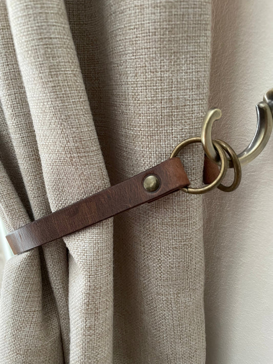 Luxury handmade leather curtain tie backs displayed on window drapes
