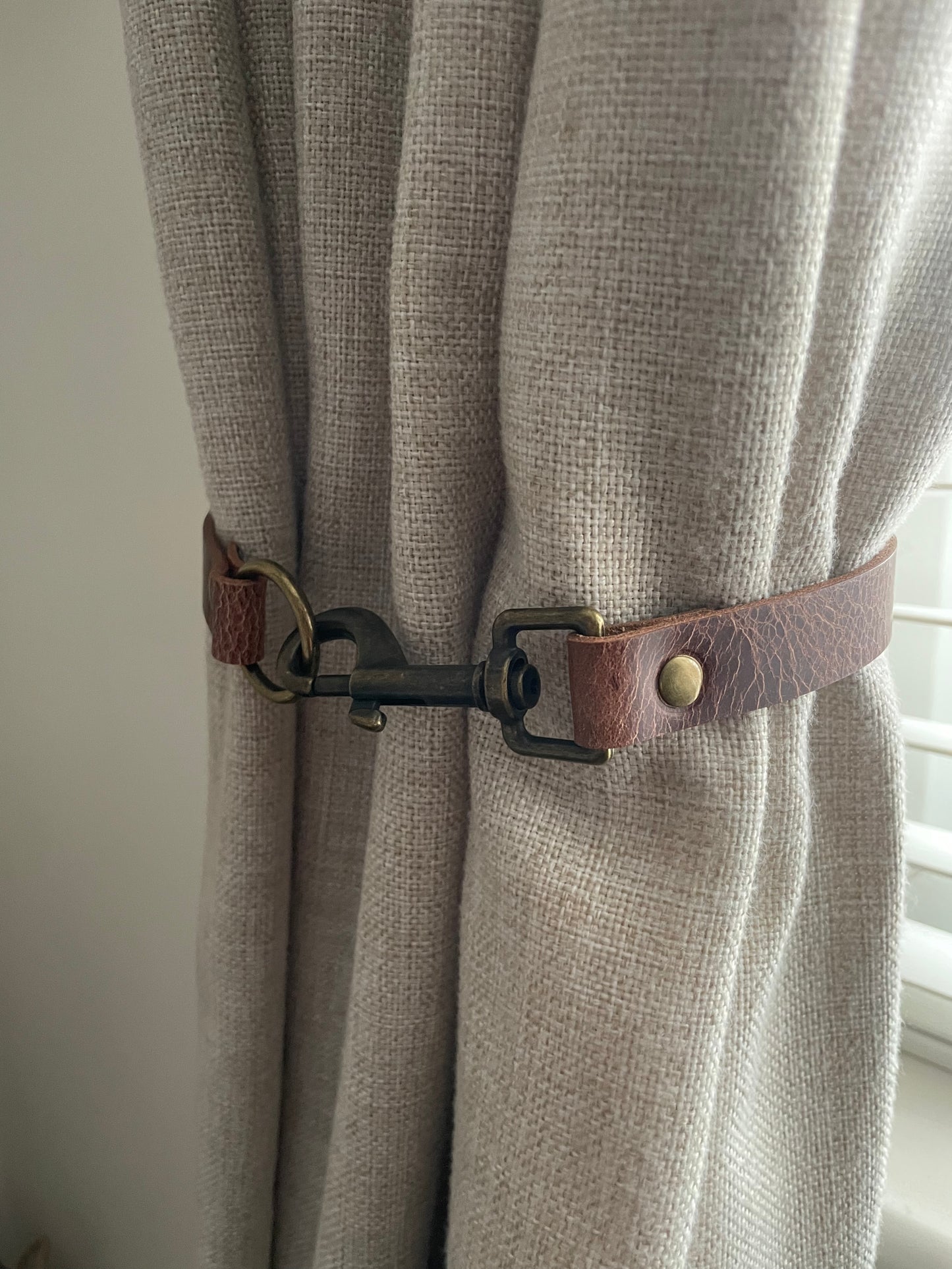 Antique brown leather curtain tie back with trigger clip fixing